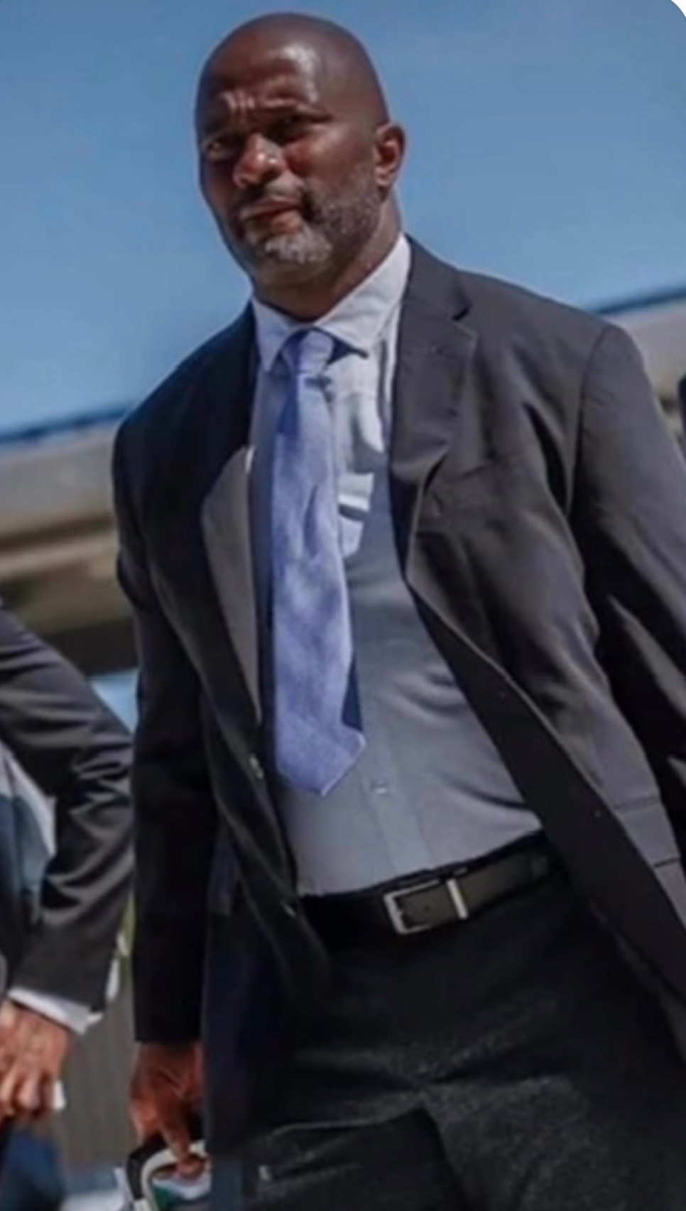 Coach Mike Bellamy — walking in black suit and blue tie